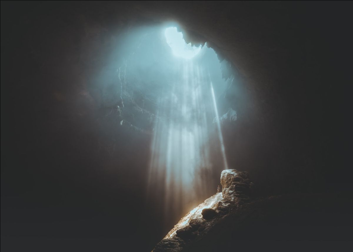 rays of light streaming into a cave from above, viewed from inside the cave.